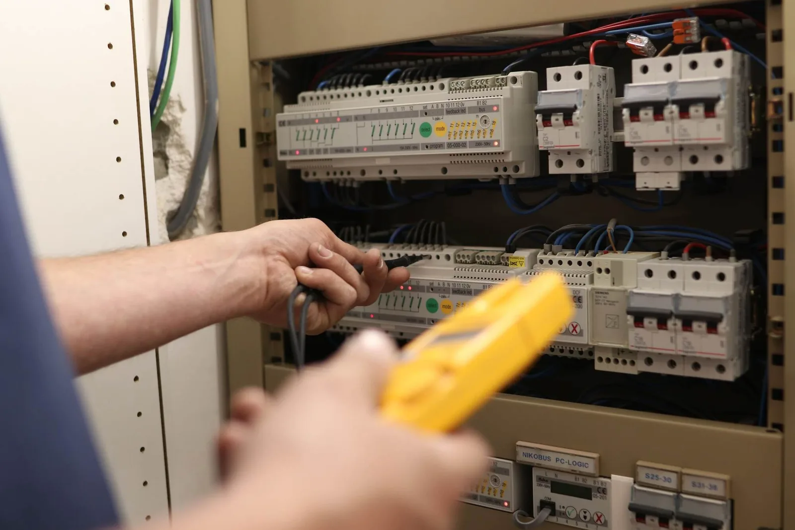 Un électricien CD Engineering mesure un tableau électrique à la pince ampèremétrique